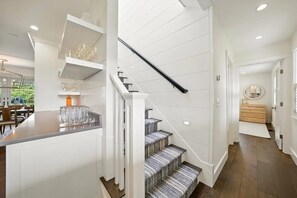 A modern kitchen with white cabinetry, a bar area, and a staircase with patterned carpet.
