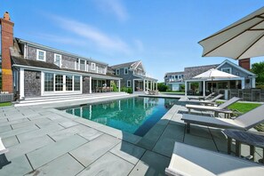A swimming pool with lounge chairs and a covered patio area.