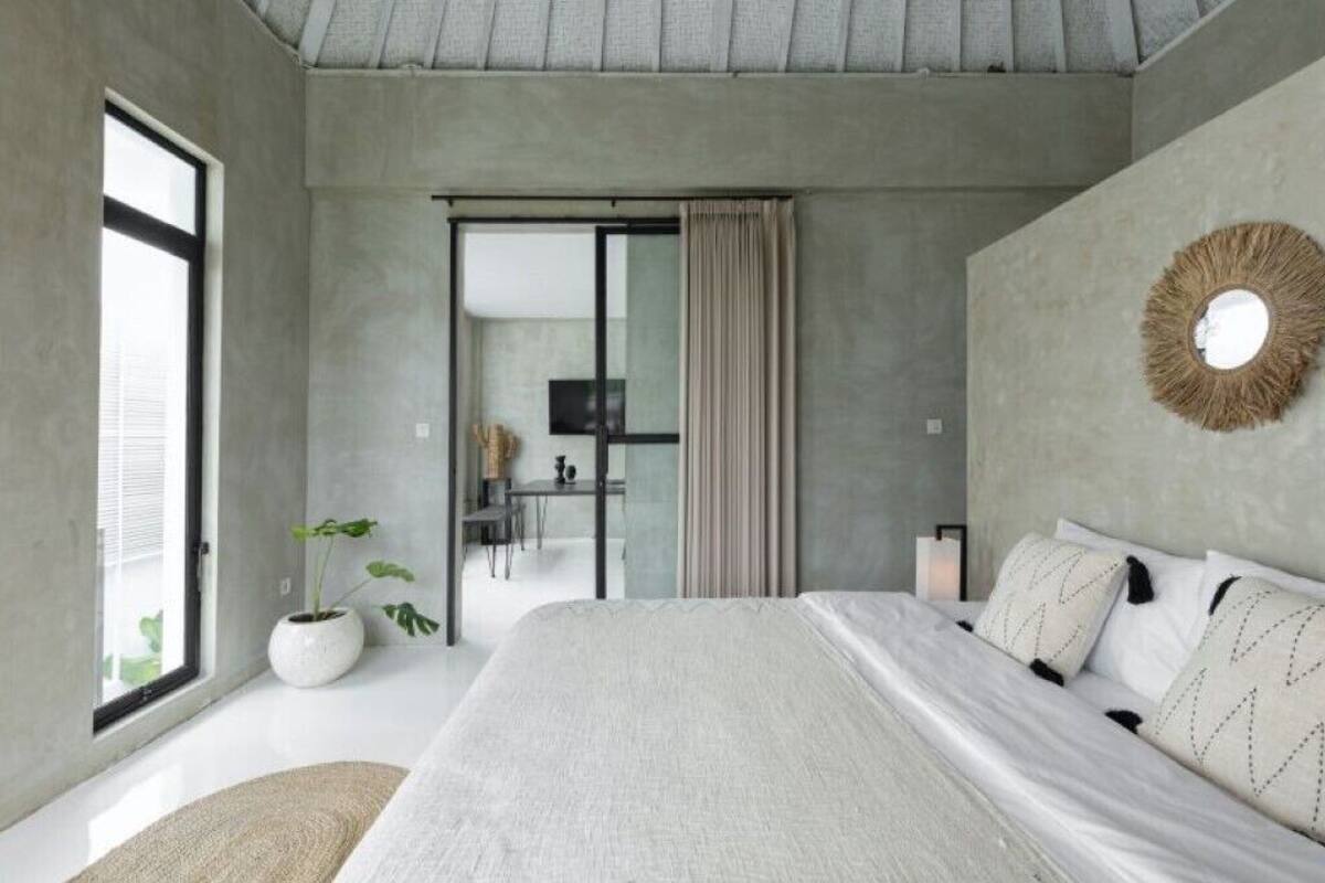 Um quarto moderno com uma cama grande, televisão, escrivaninha e um vaso de planta.