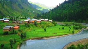 A village with traditional houses along a river, surrounded by lush green hills. - Hotel Regency Inn Dhirkot (Rawalakot)