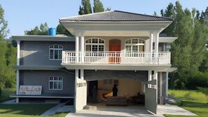 A two-story house with a balcony, a covered entryway, and a visible front yard. - Hotel Regency Inn Dhirkot (Rawalakot)
