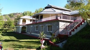 A two-story building with a balcony, a staircase, and a small garden area. - Hotel Regency Inn Dhirkot (Rawalakot)