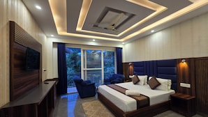 A modern bedroom with a large bed, a TV, a balcony with a view, and a ceiling with recessed lighting. - Hotel Summer Nest - Bhagsu Waterfall  (Dharamshala)