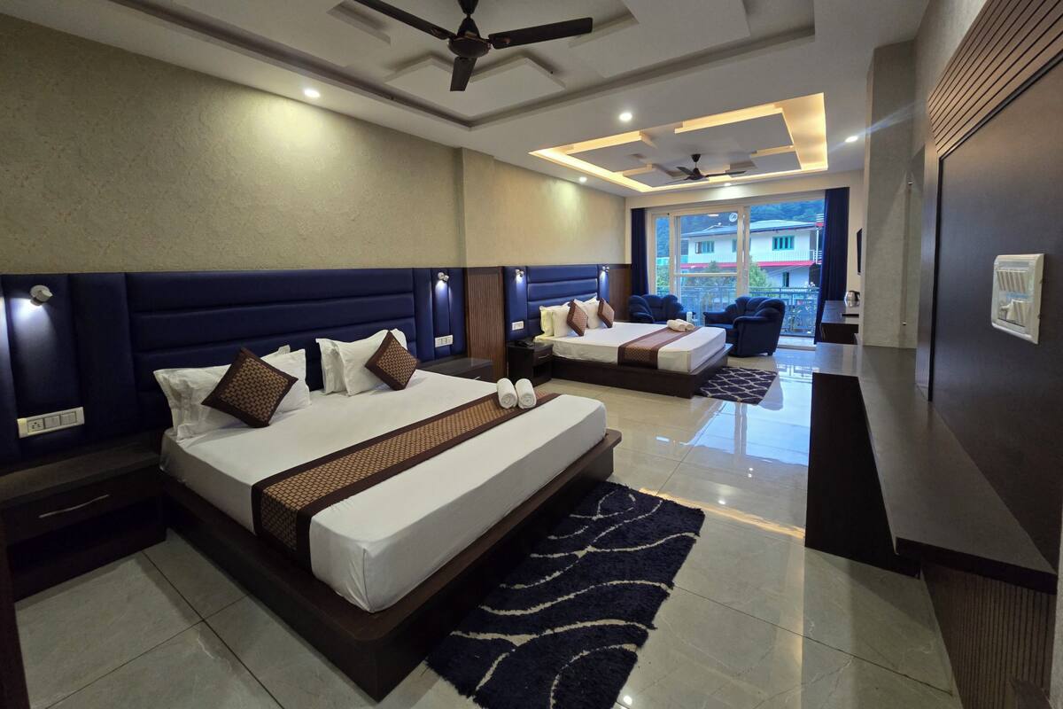 A hotel room with two beds, a ceiling fan, and a view of the outside.