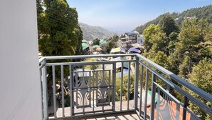A balcony with a view of a hillside village, metal railings, and a clear sky. - Hotel Summer Nest - Bhagsu Waterfall  (Dharamshala)