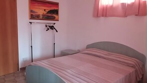 Une chambre à coucher avec un lit, un tableau accroché au mur et une fenêtre avec des rideaux.