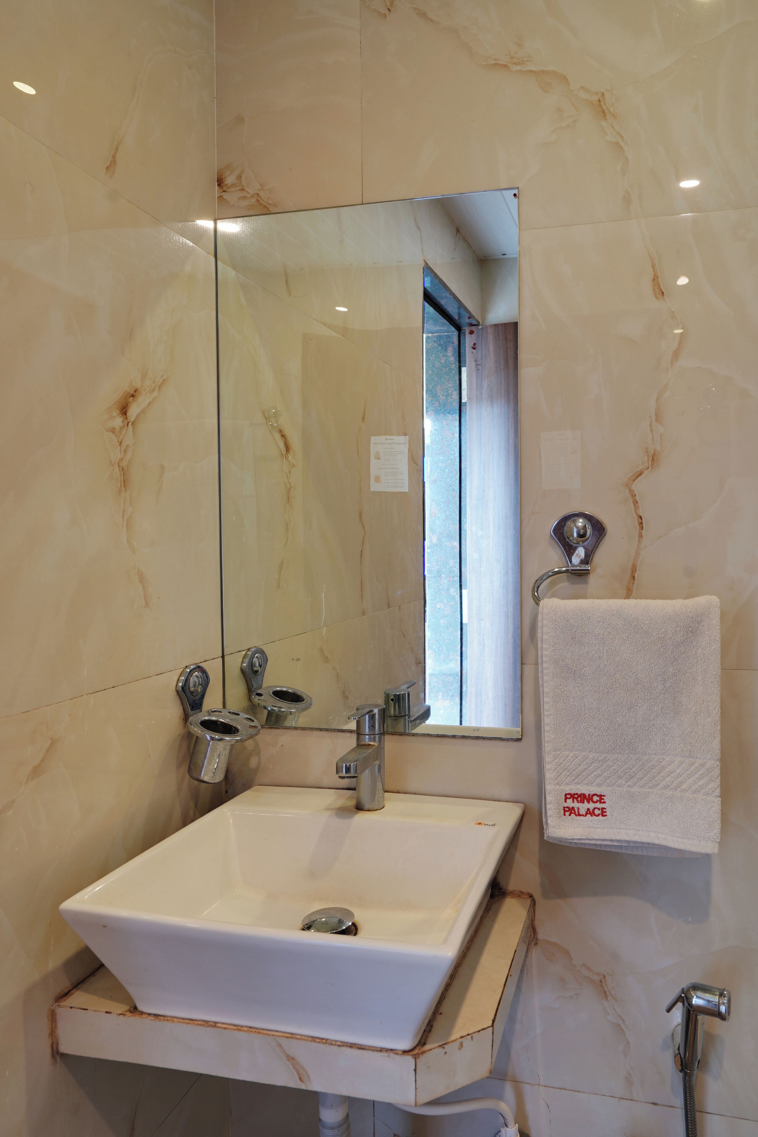 Un baño con lavamanos blanco, espejo, toallero y ducha.