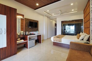 A modern hotel room with a bed, a desk, a wardrobe, a television, and a ceiling fan.