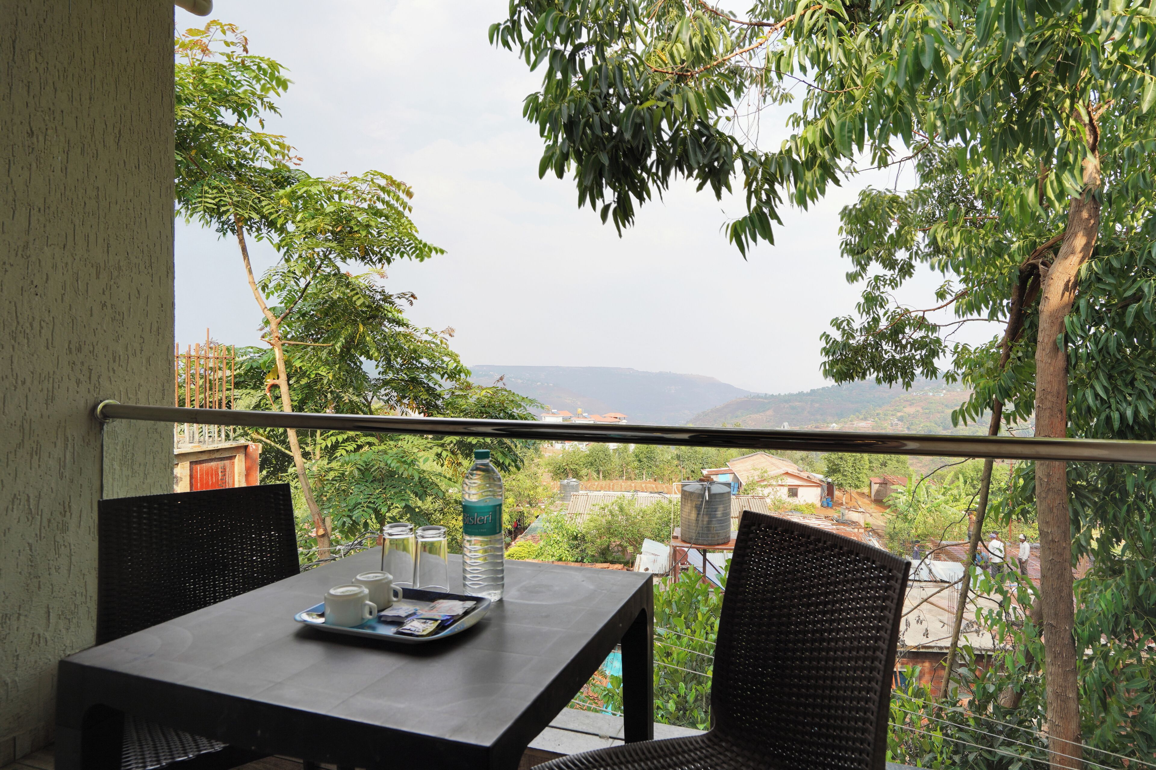 A balcony with a table, chairs, and a view of a village.