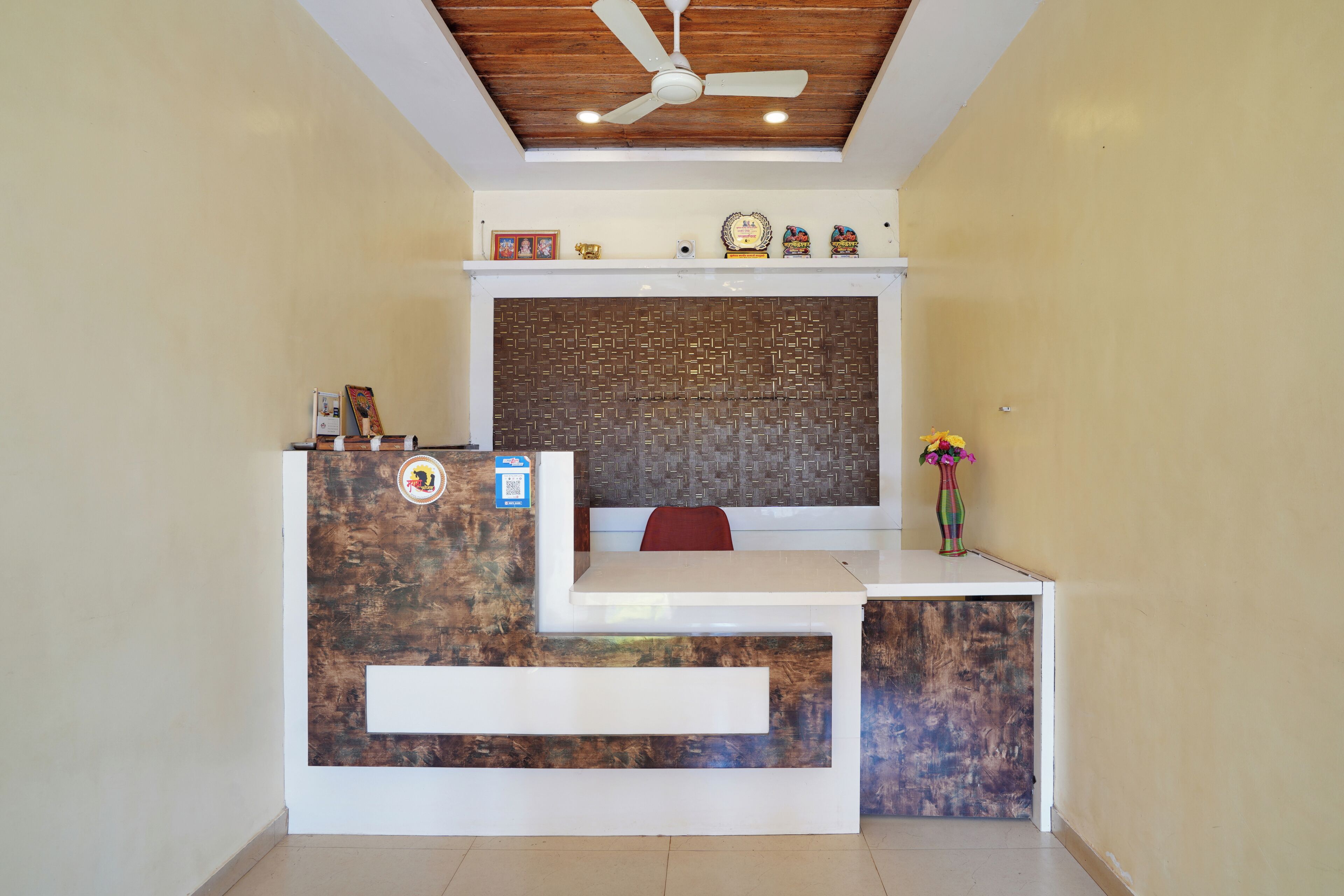 A reception desk with a ceiling fan, a decorative wall, and a small shelf with items.