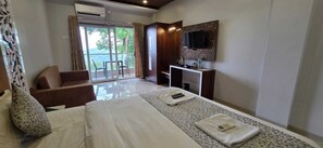 A hotel room with a bed, a desk, a TV, and a balcony with a view.
