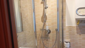 Et brusebad med glasdør, et toilet og en håndvask.