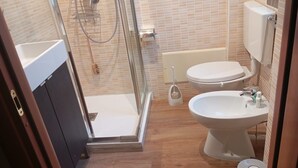 Et badeværelse med brusebad, toilet og håndvask.