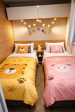 Une chambre d’hôtel avec deux lits, chacun recouvert d’une couette à motifs animaliers différents.