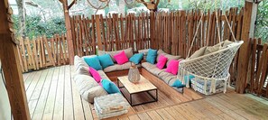 A wooden deck with a sofa, cushions, a hanging chair, and a coffee table. - COZY HOUSE - LODGING 8p LUXURY CAMPING RANGE **** (Lège-Cap-Ferret)