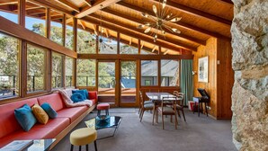 Un'ampia stanza con un divano rosso, un tavolo da pranzo e sedie, ampie finestre e un soffitto in legno.