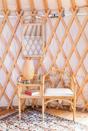 Una stanza con parete in legno intrecciato, una sedia in vimini, una lampada di vimini e un tappeto decorato.