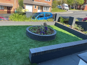 Un giardino curato con un aiuola circolare, un bordo in mattoni e una zona erbosa.