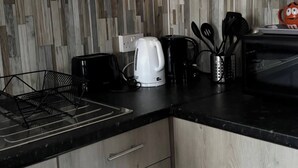 Eine Küche mit schwarzem Arbeitsplatz, einem Wasserkocher, einer Kaffeemaschine und einem Toaster.