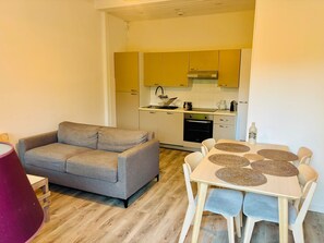 A compact living space with a sofa, dining table, and kitchenette. - Cosy apartment with garden, just a few minutes from the sea (Roquebrune-Cap-Martin)