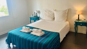 Ein Hotelzimmer mit einem Bett, zwei Nachttischen, einem Fenster und einer Lampe.