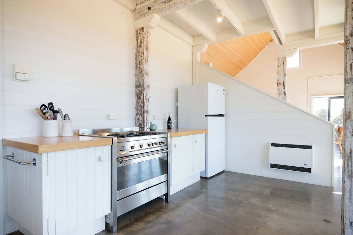 Une cuisine moderne avec des meubles blancs, une cuisinière en acier inoxydable et un plan de travail en bois.