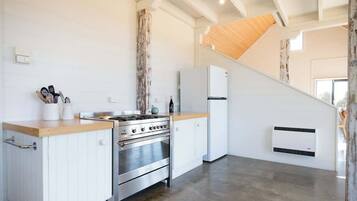 Una cocina moderna con armarios blancos, estufa de acero inoxidable y encimera de madera.