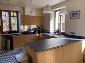 A modern kitchen with wooden cabinets, a large island, pendant lights, and a view of the outdoors. - Chalet St Gervais les bains 16 pers Les Fiz (Saint-Gervais-les-Bains)