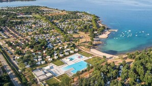 An aerial view of a coastal resort with multiple bungalow-style accommodations, a central swimming pool, and a marina with boats. - Comfort Plus Stay by Adriatic for 7 (Brtonigla)
