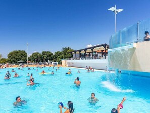 En offentlig swimmingpool med flere baner, et vandrutsjebane og et overdækket siddeområde.