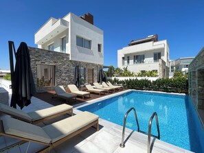Un espace piscine moderne, doté de chaises longues et d’une piscine à l’eau d’un bleu cristallin.