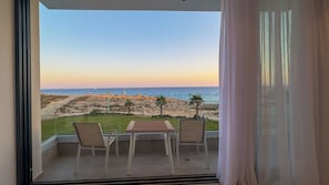 A balcony with a table and chairs, overlooking a beach with a clear view of the sea and rocky terrain. - Aqua Beachfront Villas #1, Aqua Beachfront Villas - Villa 1 (Ayia Napa)