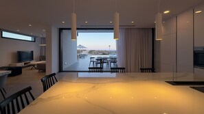 Una cocina moderna con una isla grande, comedor y vista a la playa.