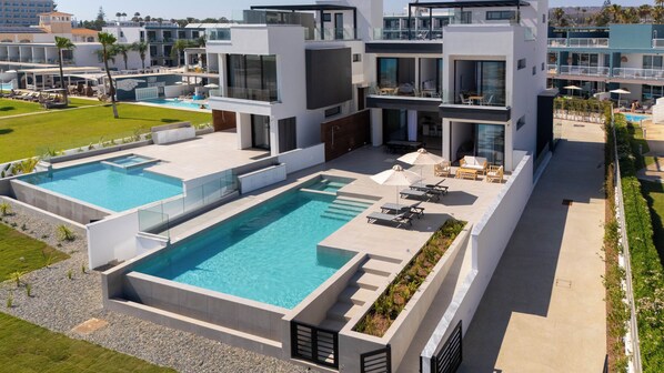 Un hotel moderno con piscina en la azotea, mobiliario exterior y vistas del paisaje circundante.