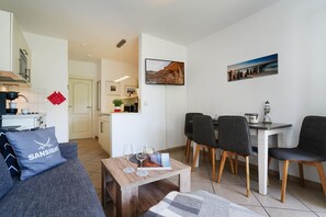 Ein modernes Wohnzimmer mit einer Couch, einem Couchtisch und einem Essbereich mit Stühlen und Tisch.