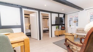 Una sala de estar moderna con una mesa de comedor de madera, un sofá, un televisor y un mueble bajo.