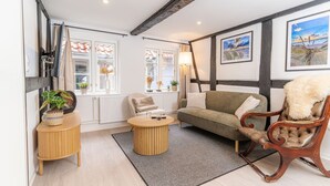 Una sala de estar acogedora con sofá, sillón, mesa de centro y plantas en macetas.