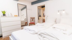 A bedroom with a bed, a dresser, a chair, a mirror, and a small plant. - fewo1846 - Matrosenkoje - fewo1846 - Matrosenkoje - centrally located (Flensburg)
