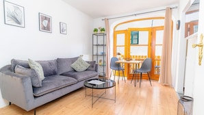 Een woonkamer met een bank, een salontafel en een eethoek met stoelen en een tafel.