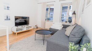 A modern living room with a flat-screen TV, grey sofa, and a small round table. - fewo1846 - Sternkoje - fewo1846 - Sternkoje - ideal for a relaxing time out (Flensburg)