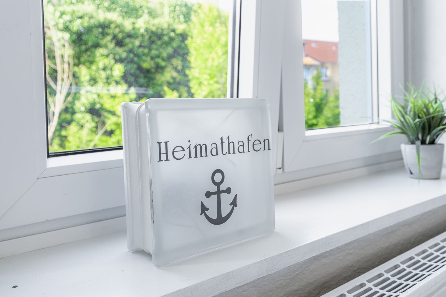 A white book with 'Heimathafen' and an anchor symbol on a windowsill.