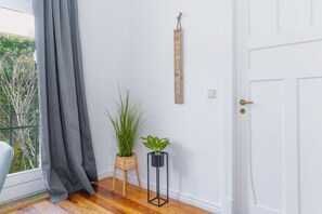 A room with a white door, a grey curtain, a wooden sign, and two potted plants. - fewo1846 - Berth Marina (Flensburg)