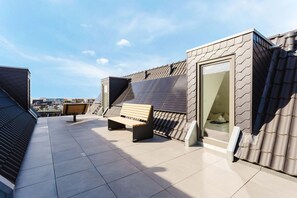 A rooftop terrace with a bench, a glass door, and solar panels. - MEERholung FeWo 4.4 - Modern penthouse on two levels with lots of comfort - (Cuxhaven)