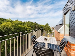 A balcony with a table and chairs, a bottle of wine, and a bowl of snacks. - MEERholung FeWo 4.4 - Modern penthouse on two levels with lots of comfort - (Cuxhaven)