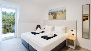 Hotellihuone, jossa on kaksi sänkyä, suuri ikkuna, taulu ja peili.