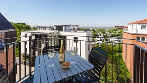 A balcony with a table set for two, a bottle of wine, and a bowl of nuts. - MEERholung FeWo 4.10 - Exclusive penthouse with sea view & roof terrace flair - (Cuxhaven)
