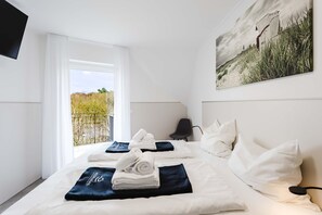 A hotel room with a bed, a chair, a TV, and a painting on the wall. - MEERholung Vacation Rental 4.7 – Large 2-Bedroom Penthouse Apartment for Up to 7 Guests (Cuxhaven)