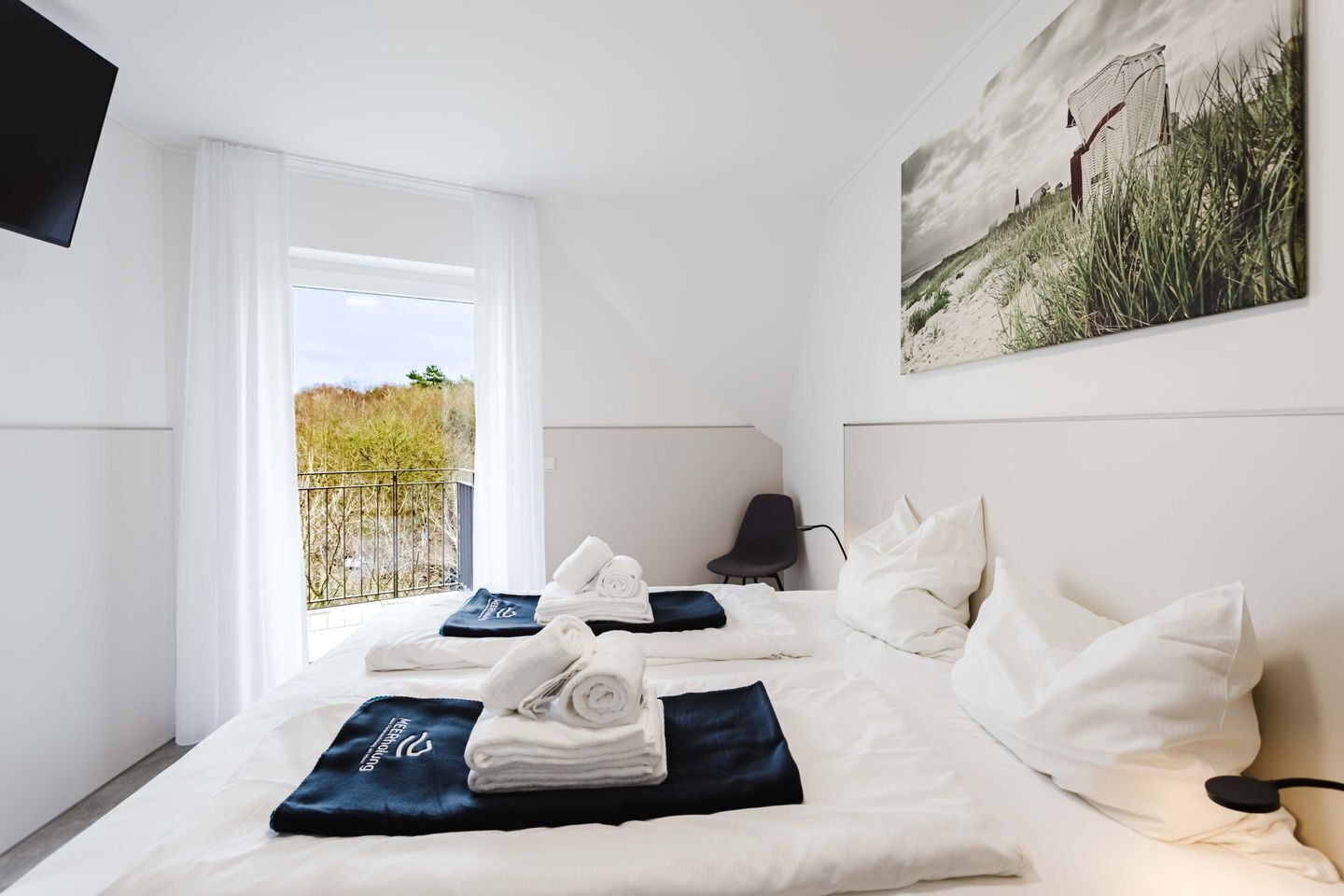 Ein Hotelzimmer mit Bett, Sessel, Fernseher und einem Bild an der Wand.