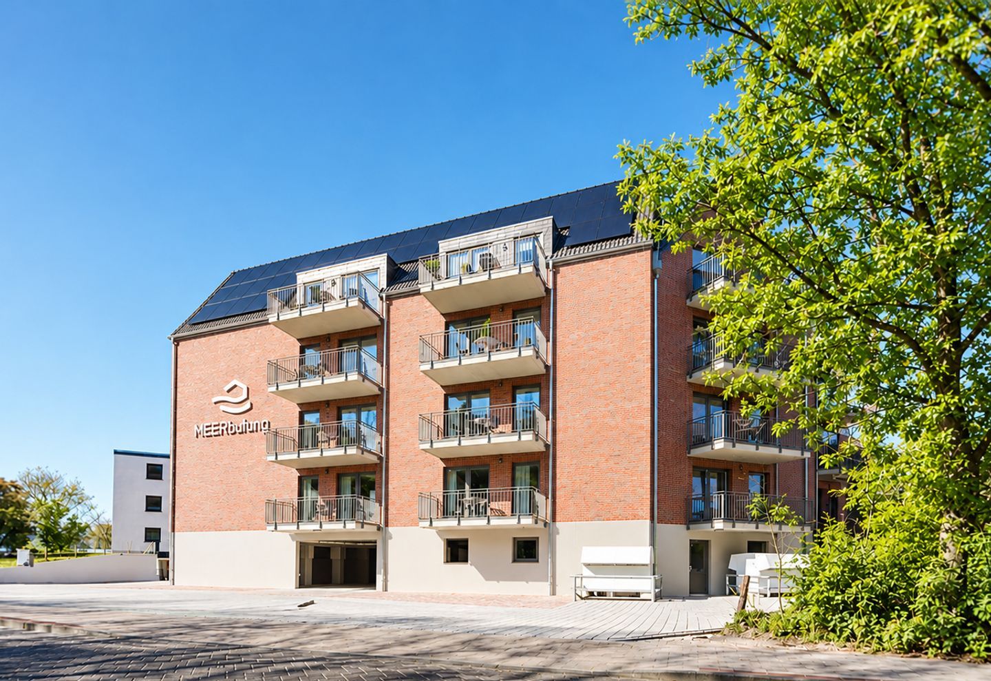 A multi-story building with a brick facade, balconies, and a clear sky.