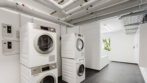 A modern laundry facility with stacked washers and dryers, a control panel, and a view of the outdoors. - MEERholung Vacation Rental 2.10 1-Raum-Apartment, 400 m from the beach - MEERholung House (Cuxhaven)